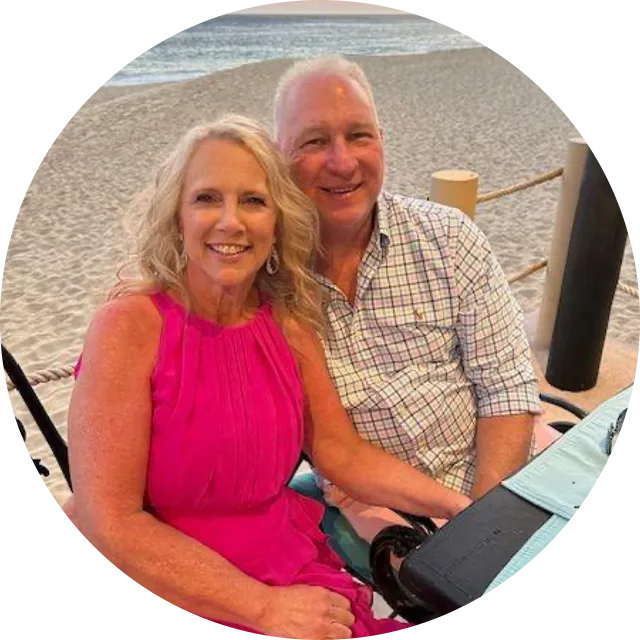Coach Bill Jenkins with his wife Christie, sitting together on a beach at sunset.