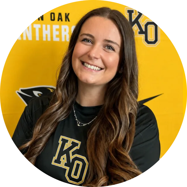 Coach Logan Studdard in a Klein Oak shirt, smiling in front of a gold Klein Oak Panthers backdrop.